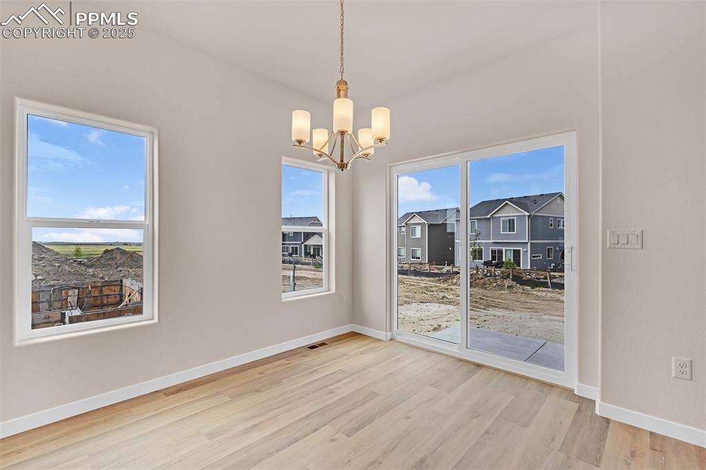 Unfurnished dining area featuring light wood finished floors and a chandelier