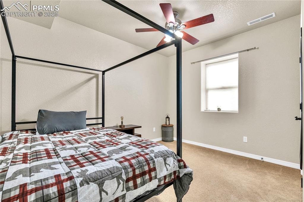 Carpeted bedroom featuring a textured ceiling and ceiling fan