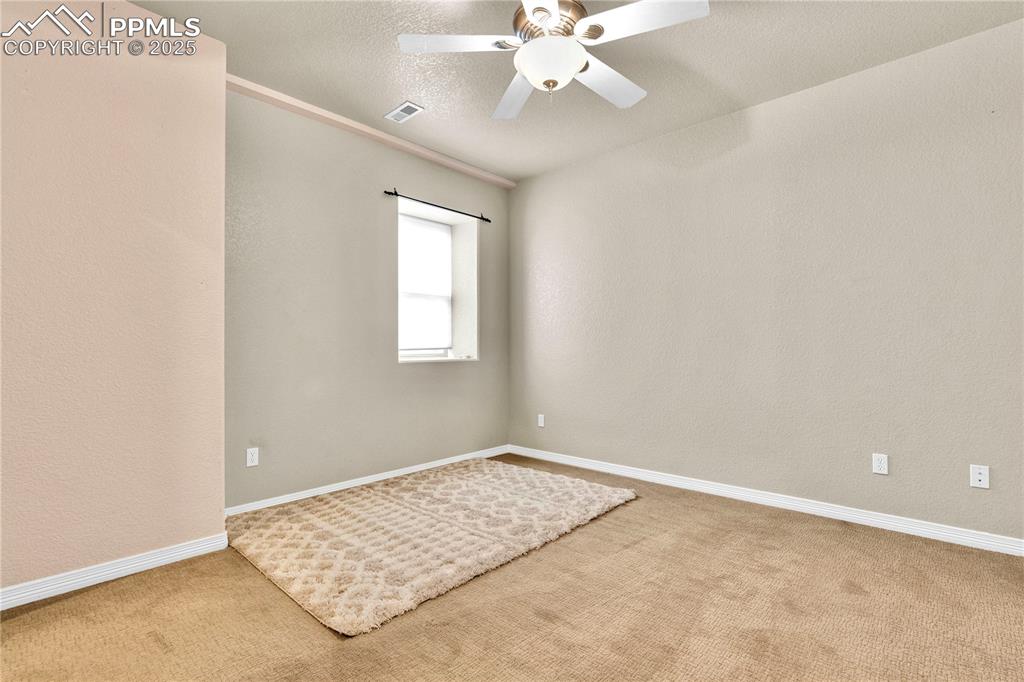 Spare room with carpet floors, a textured wall, a textured ceiling, and ceiling fan