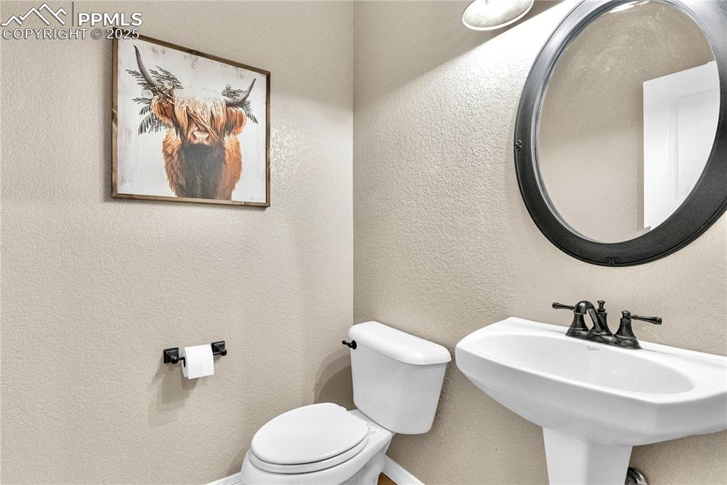 Half bath with toilet and a textured wall