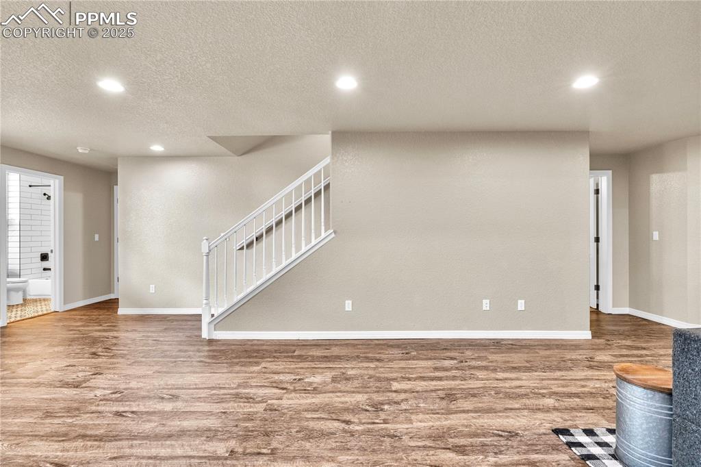 Unfurnished living room featuring recessed lighting, a textured ceiling, wood finished floors, and stairway