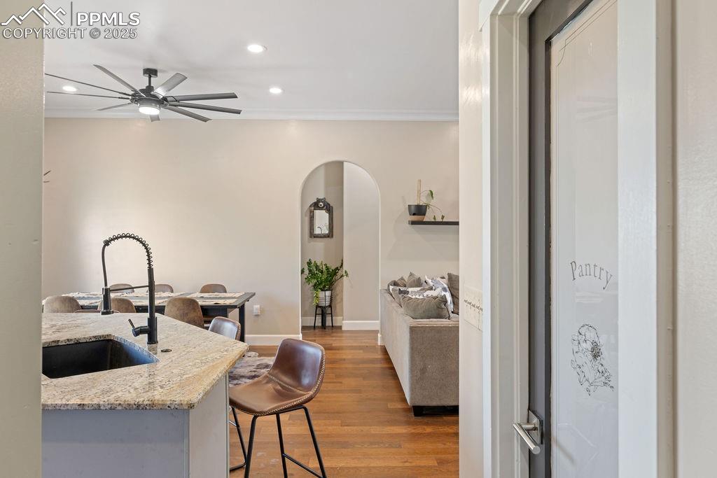 Kitchen with dark wood-style floors, arched walkways, recessed lighting, a kitchen bar, and light stone countertops