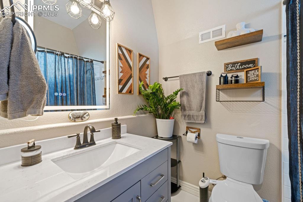 Bathroom featuring a shower with curtain, vanity, and a textured wall