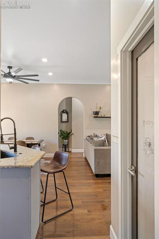 Kitchen featuring arched walkways, dark wood finished floors, recessed lighting, light stone countertops, and ceiling fan