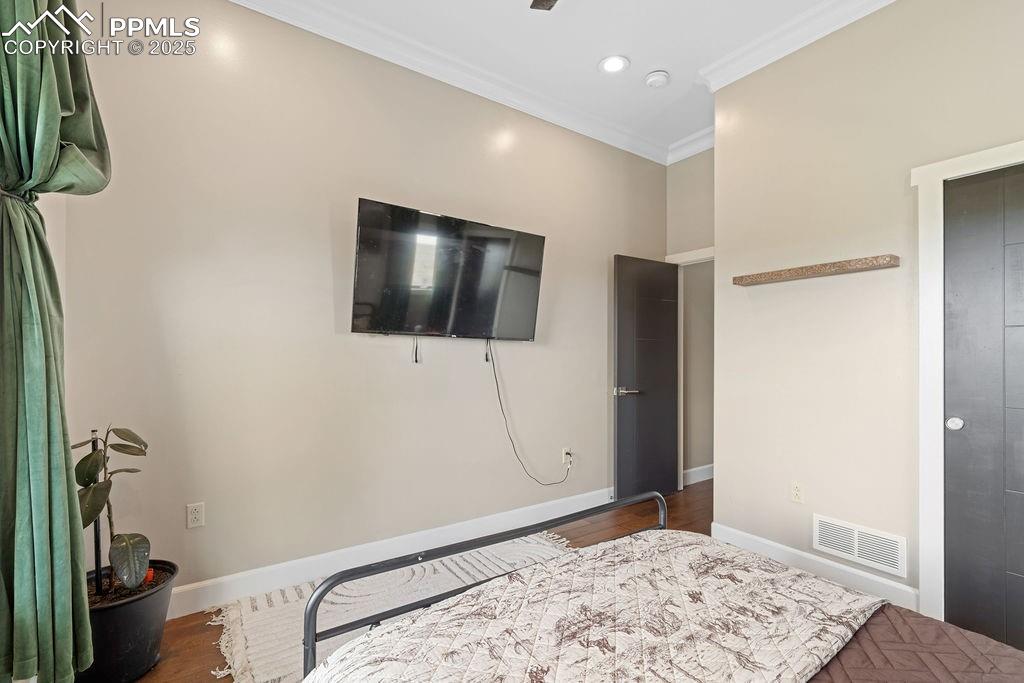 Bedroom with crown molding, wood finished floors, and recessed lighting