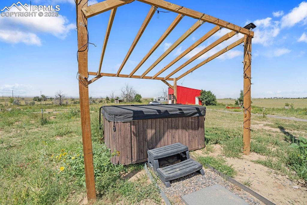 View of yard with a pergola, a view of countryside, a hot tub, and a patio area