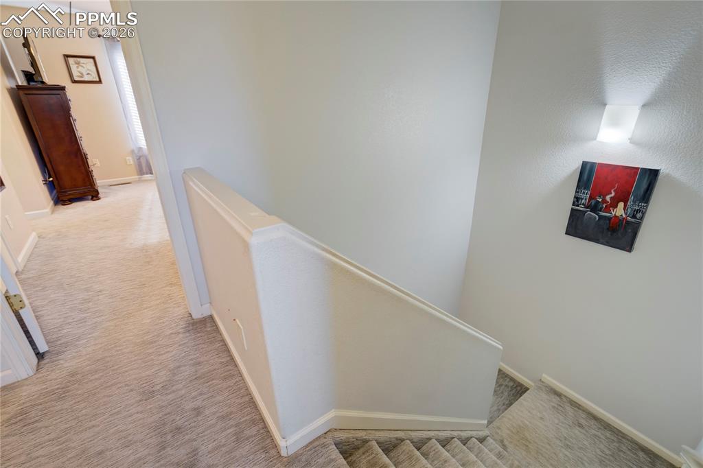 Hall with light colored carpet and an upstairs landing