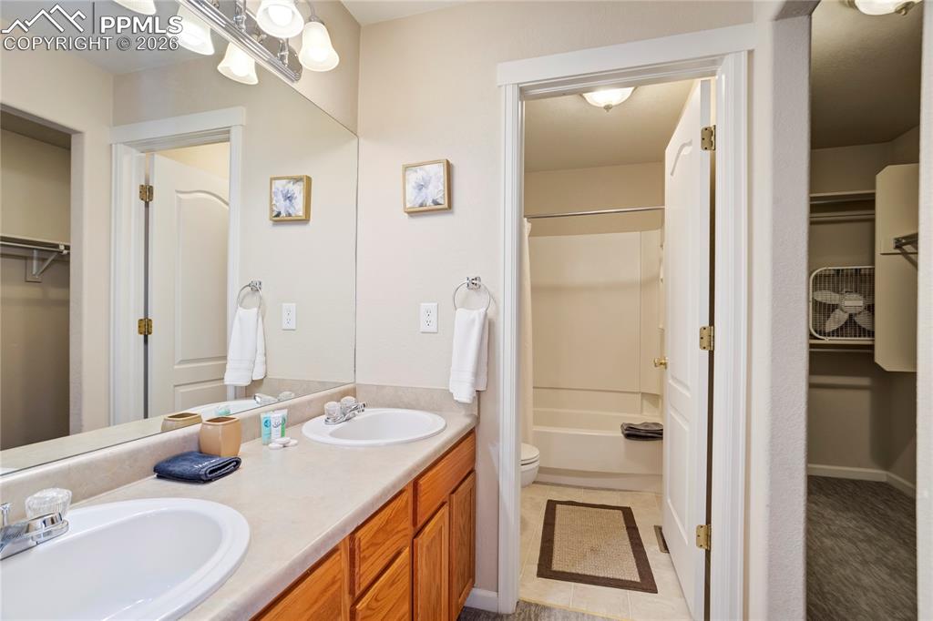Full bathroom featuring a spacious closet, double vanity, and bathtub / shower combination