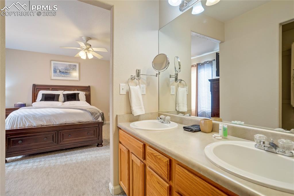 Full bathroom with double vanity, ensuite bath, and ceiling fan