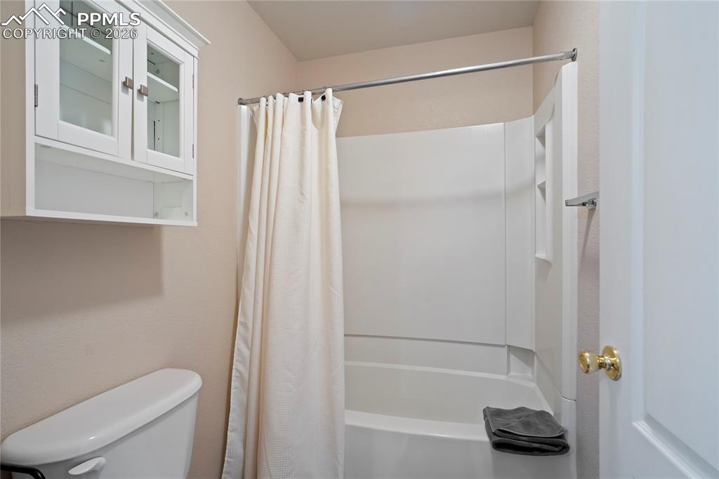 Full bath featuring shower / bath combo with shower curtain and toilet