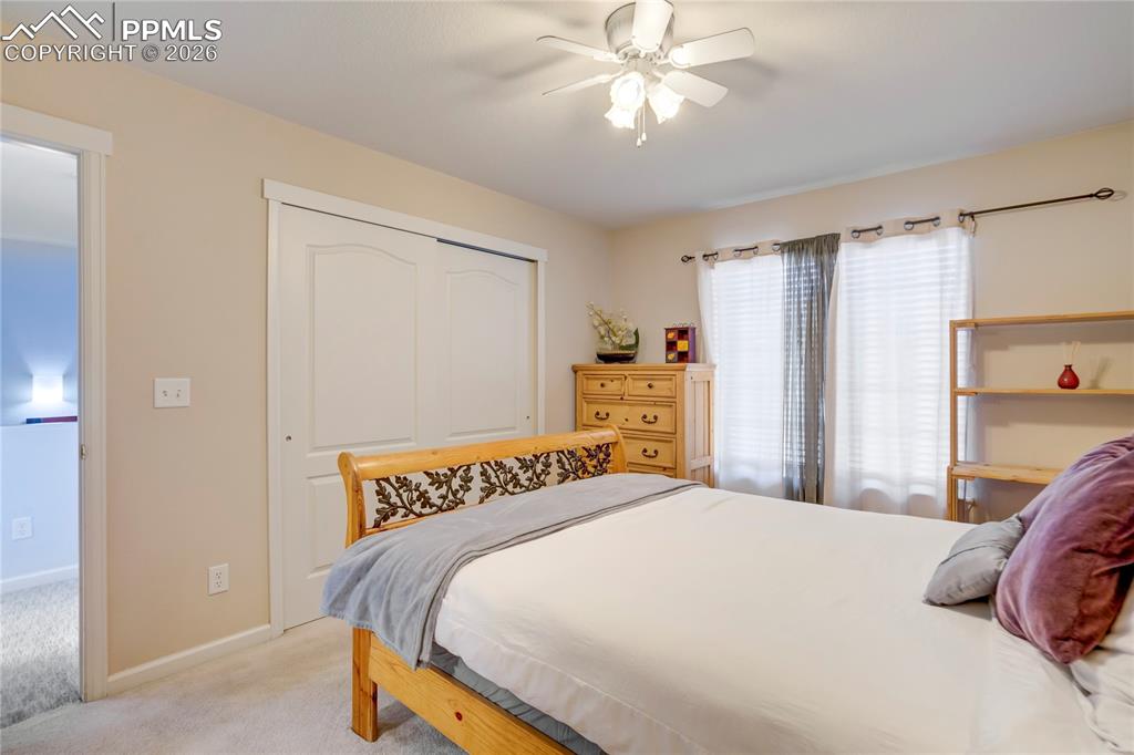 Bedroom with light carpet, a closet, and a ceiling fan