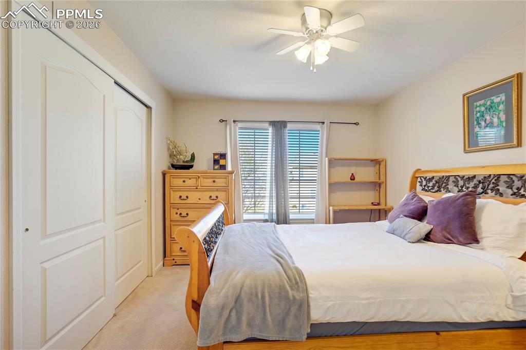 Bedroom with light carpet, a closet, and ceiling fan