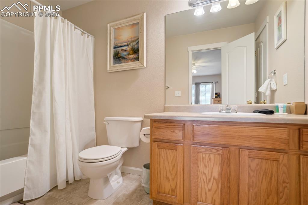 Full bath with shower / bath combination with curtain, vanity, and light tile patterned floors