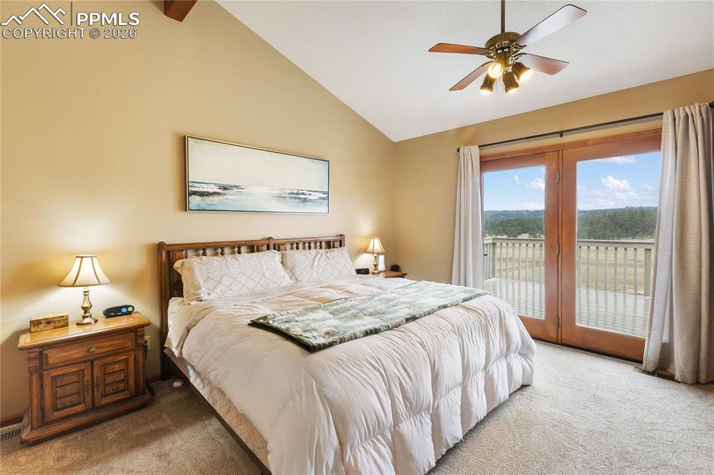 The main bedroom has a vaulted ceiling with a rich wooden beam and a ceiling fan, and enjoys direct access to the deck!
