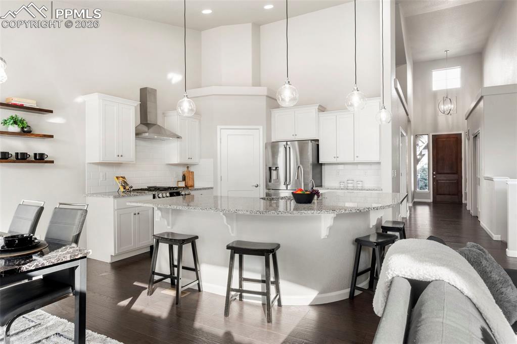 Kitchen featuring a high ceiling, dark wood finished floors, white cabinetry, stainless steel appliances, and a spacious island