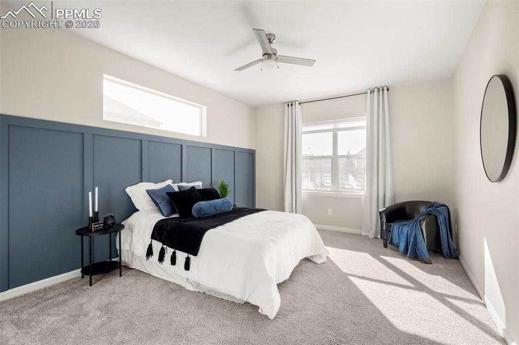 Bedroom featuring a decorative wall, a ceiling fan, and light colored carpet