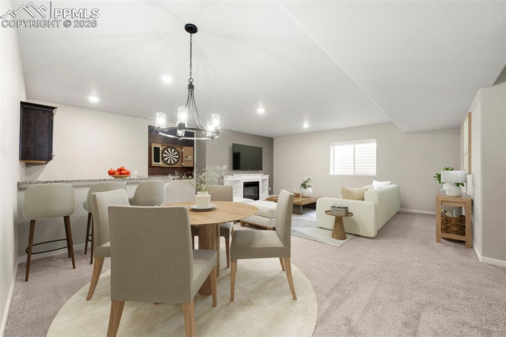 Dining room featuring light carpet, a glass covered fireplace, and hanging lights