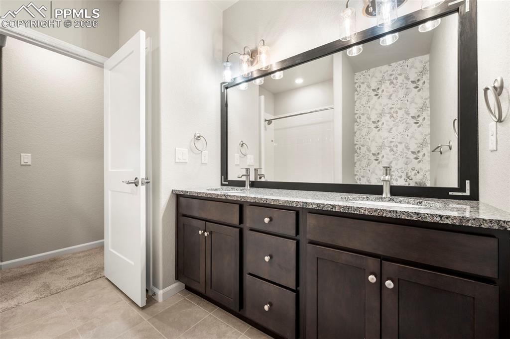 Full bath with double vanity and light tile patterned floors