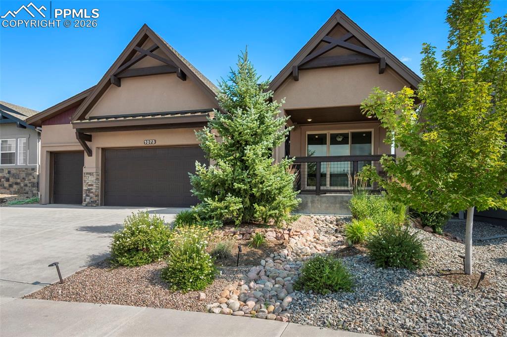 Craftsman inspired home with stucco siding, a garage, driveway, and stone siding