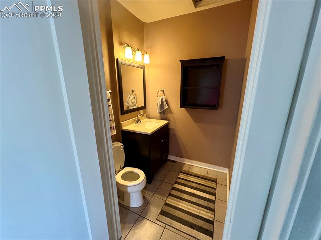 Bathroom featuring toilet, tile floors, and vanity