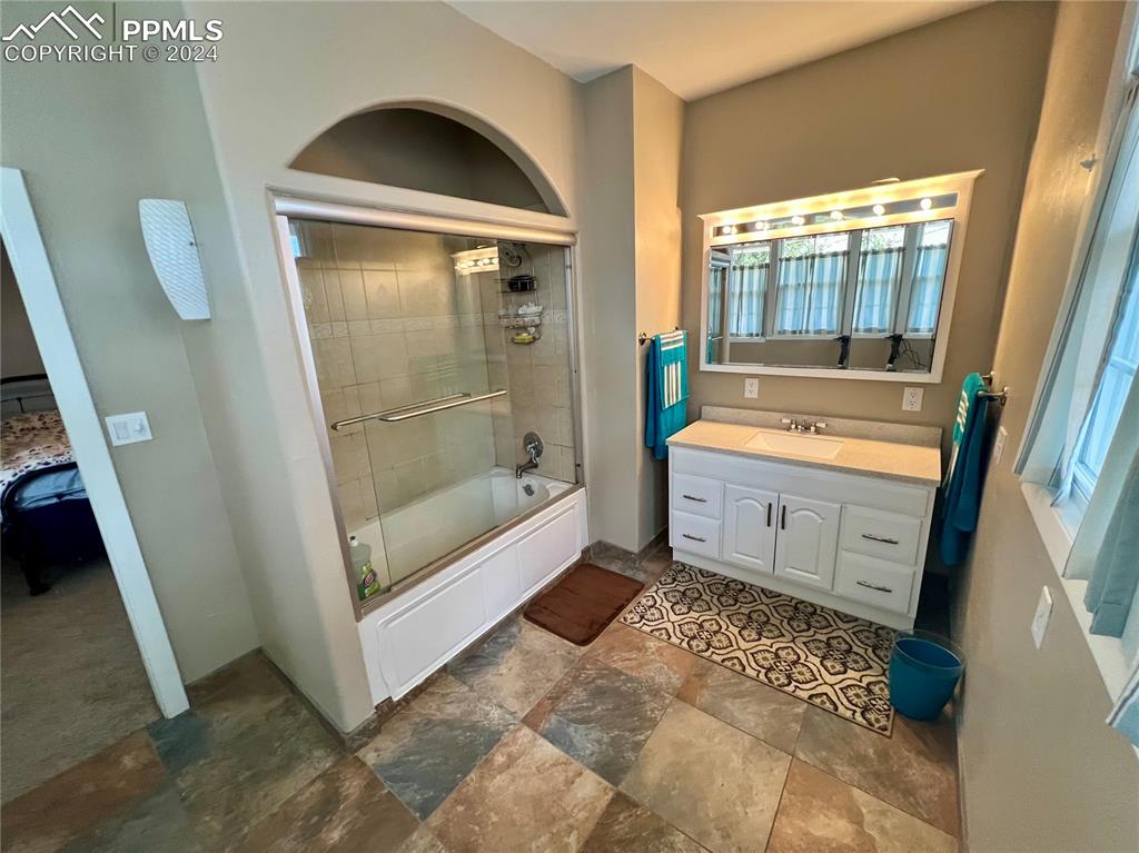 Bathroom featuring plenty of natural light, shower / bath combination with glass door, vanity, and tile floors