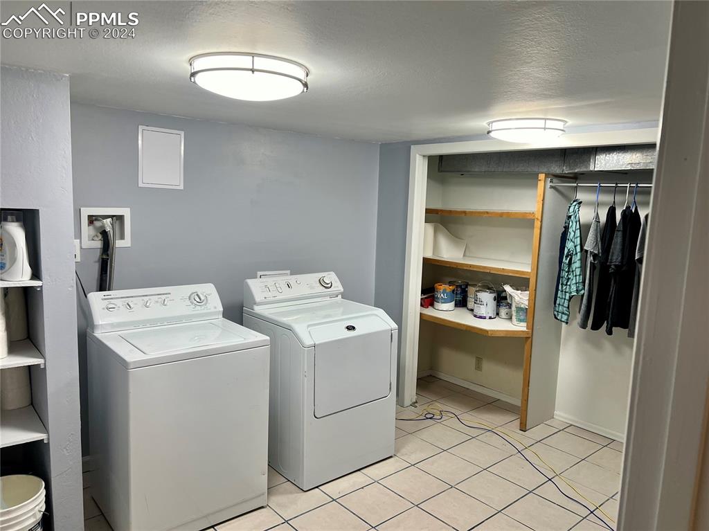 Clothes washing area featuring washer hookup, washing machine and clothes dryer, and light tile floors