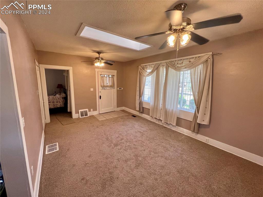 Carpeted empty room featuring a textured ceiling and ceiling fan