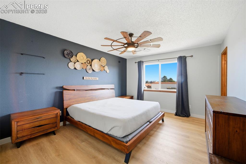Bedroom featuring light wood-style flooring, a textured ceiling, and a ceiling fan