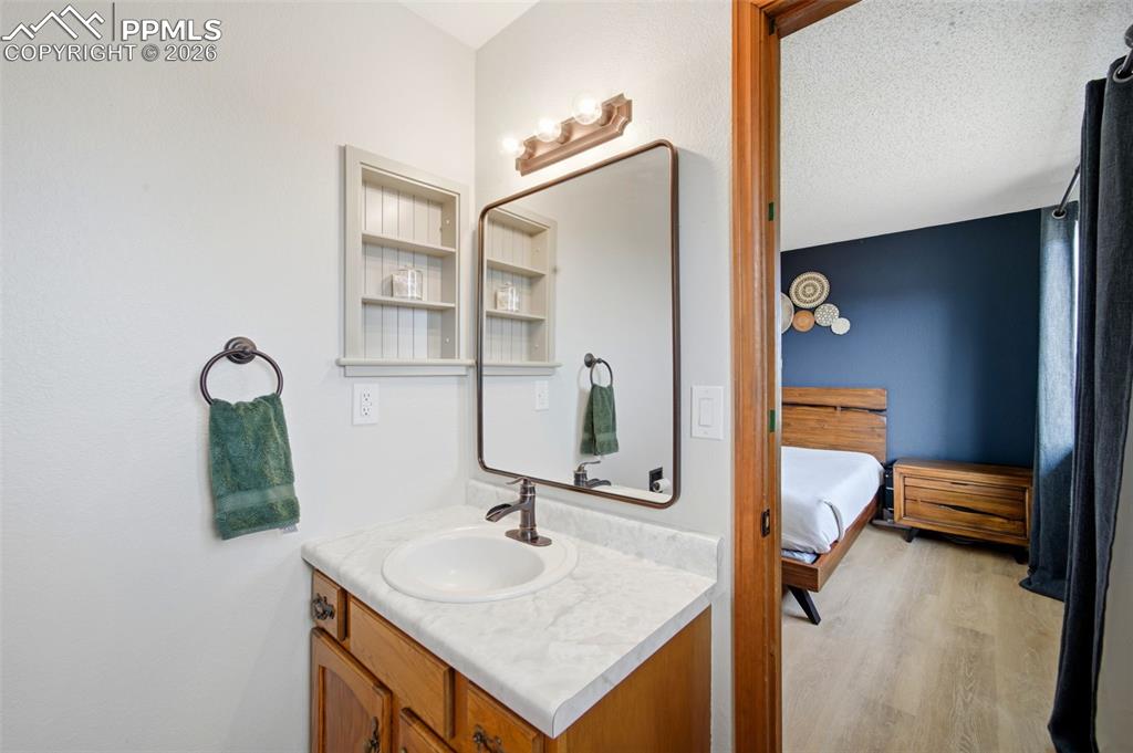 Ensuite bathroom with vanity, light wood-type flooring, and a textured ceiling