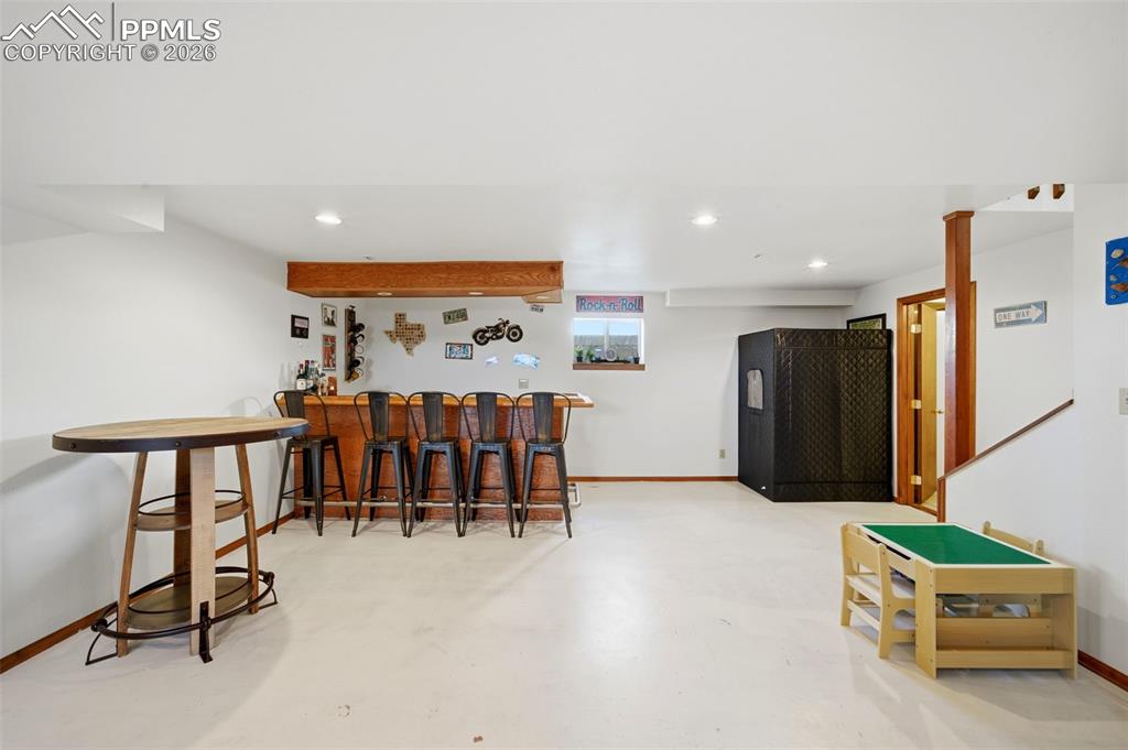 Indoor dry bar featuring finished concrete flooring and recessed lighting