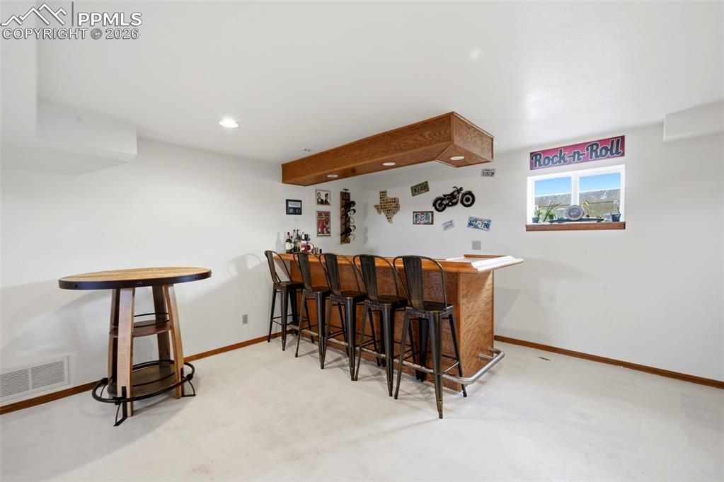Indoor dry bar featuring concrete floors and recessed lighting
