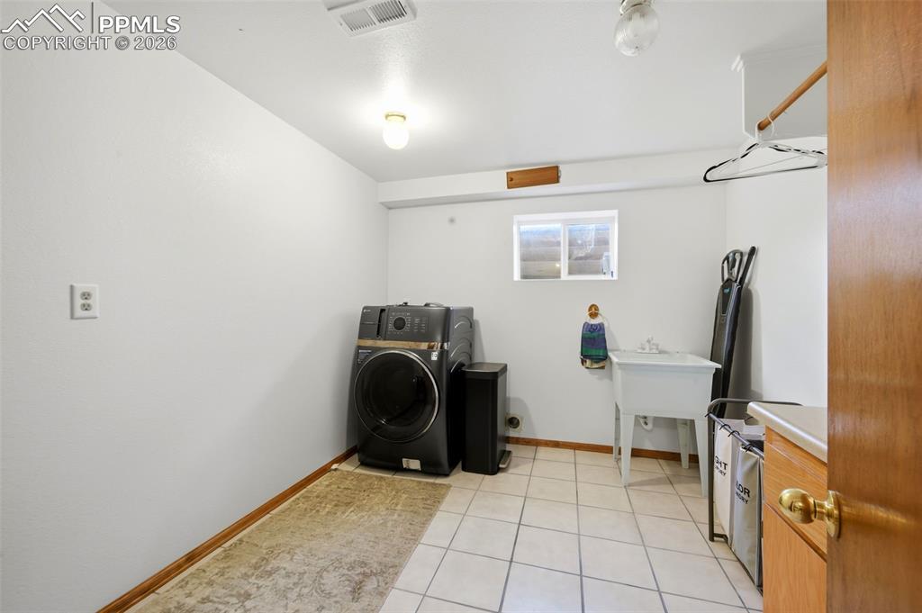 Laundry area with washer / clothes dryer and light tile patterned floors