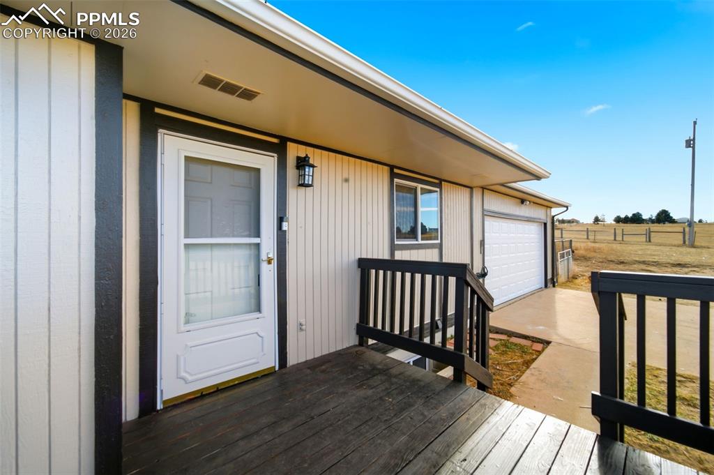 Entrance to property featuring a garage, driveway, and a deck