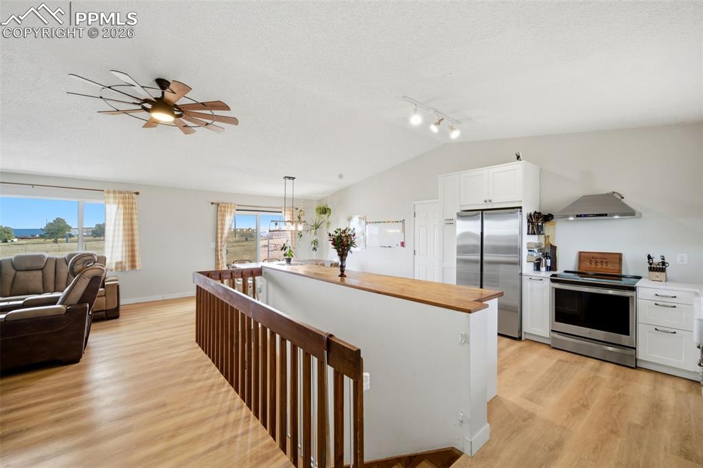 Kitchen featuring white cabinetry, appliances with stainless steel finishes, butcher block countertops, a kitchen island, and light wood-style floors