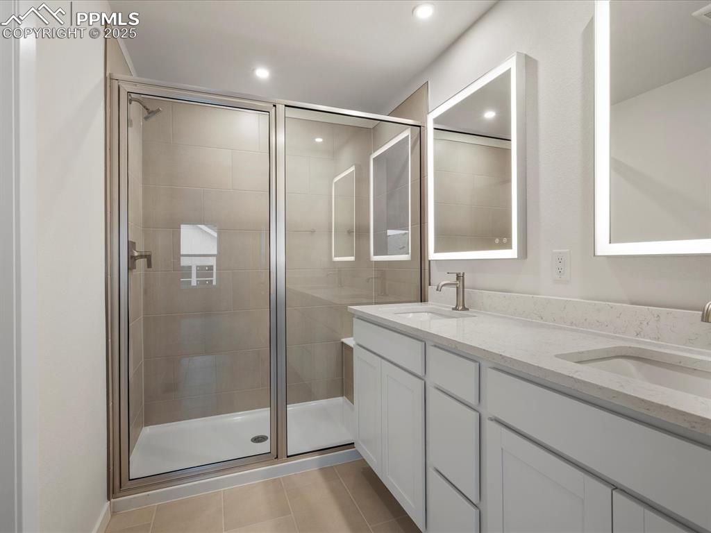 Bathroom featuring double vanity, a stall shower, tile patterned flooring, and recessed lighting