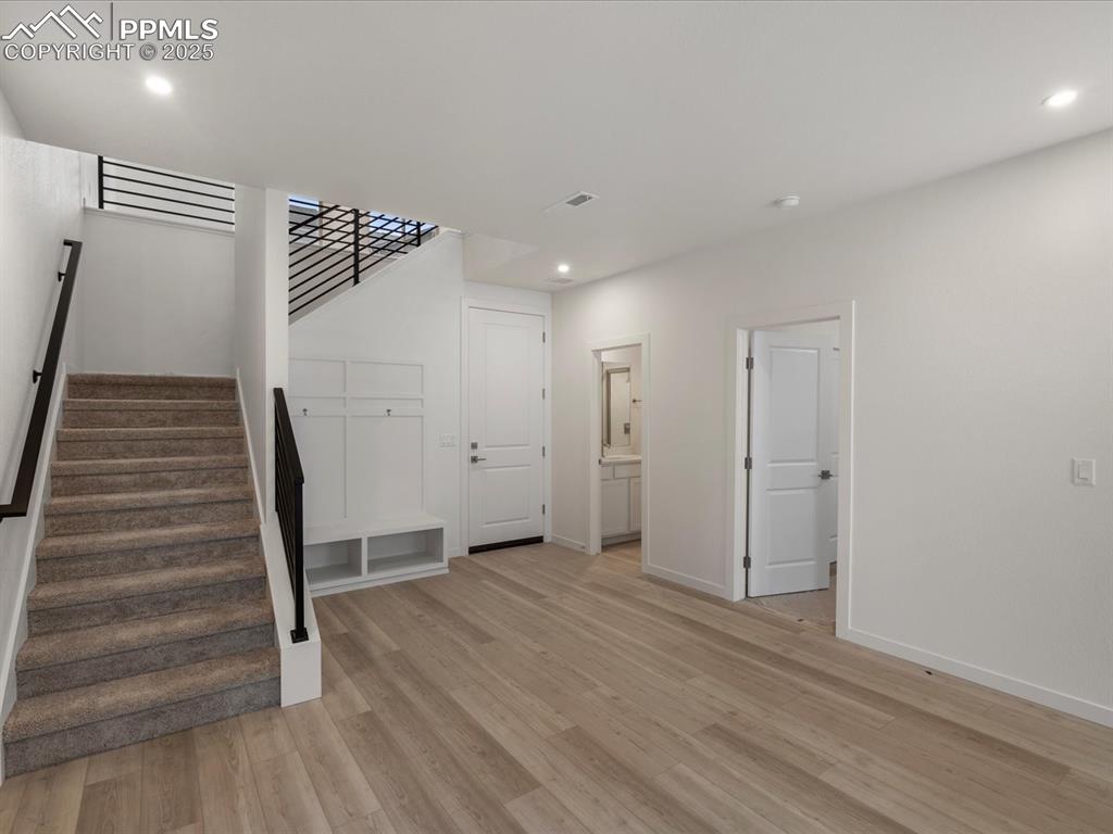 Unfurnished living room featuring stairway, light wood-type flooring, and recessed lighting