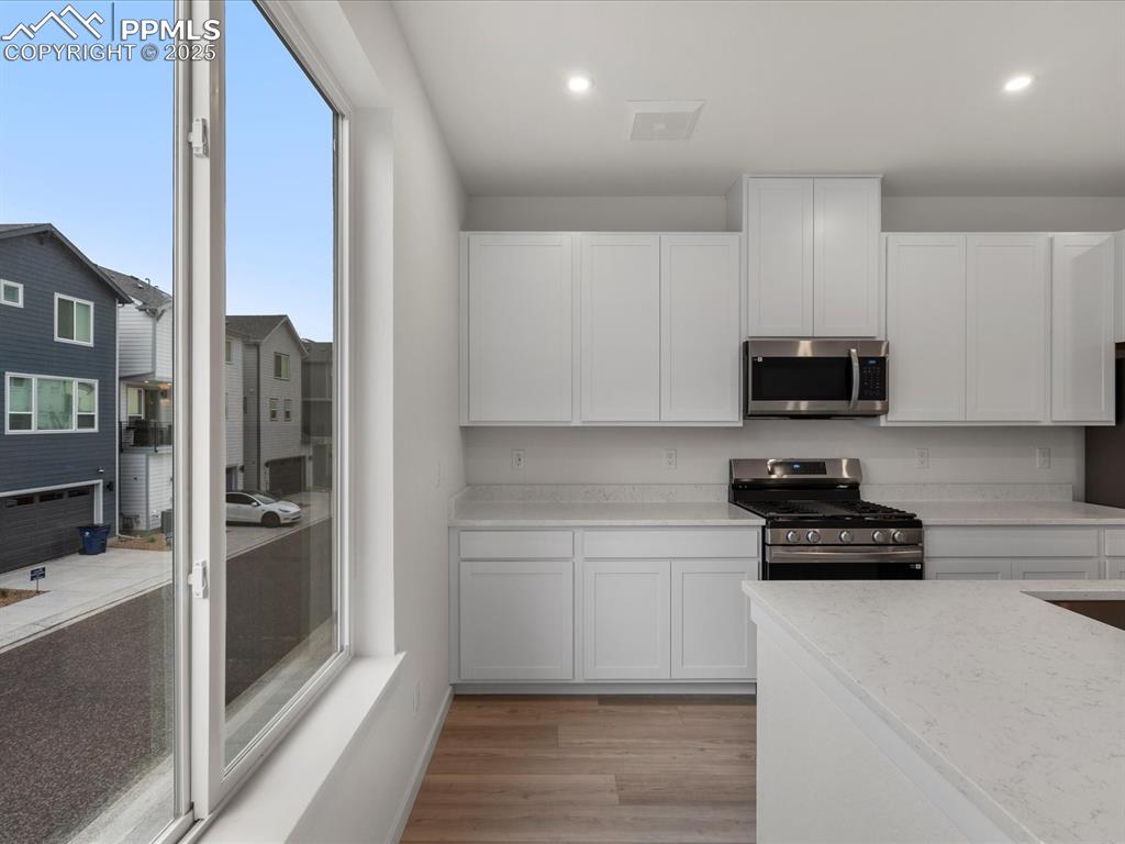 Kitchen featuring stainless steel appliances, white cabinets, light wood-style floors, and recessed lighting