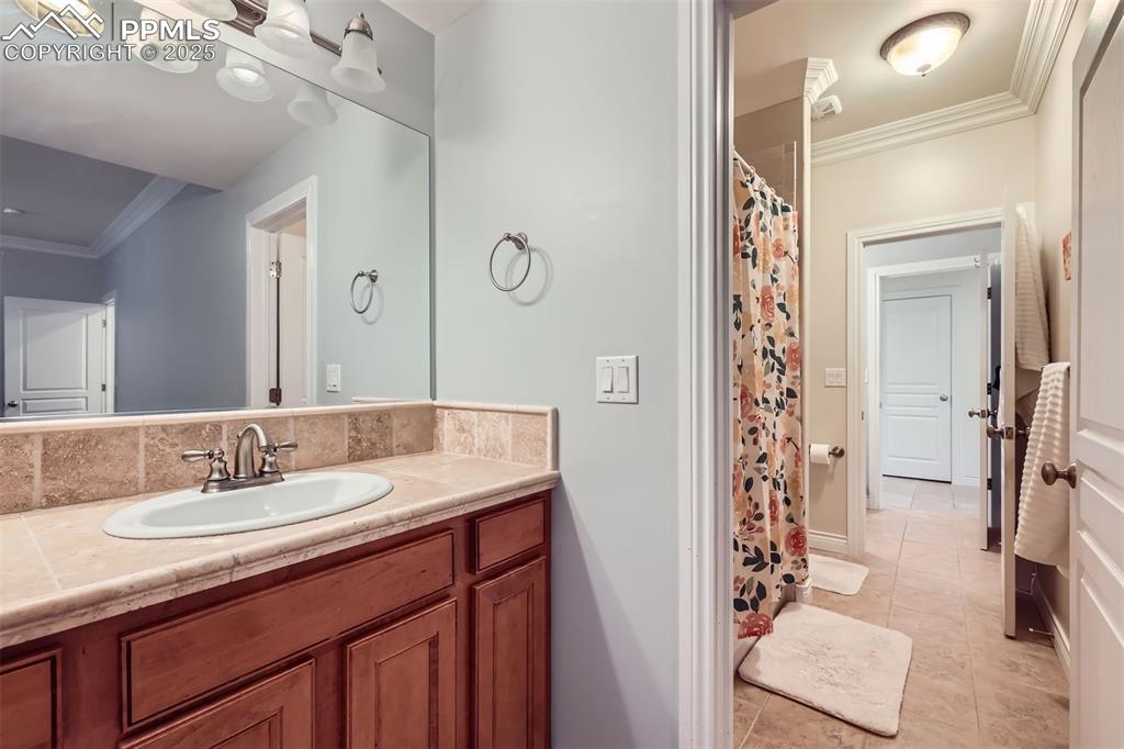Full bathroom featuring vanity, ornamental molding, tile patterned flooring, and curtained shower