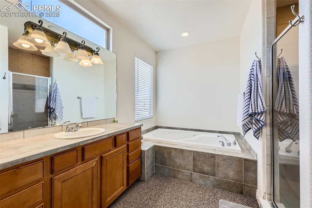 5-piece master bathroom with vanity, a bath, a shower stall, and tile patterned floors