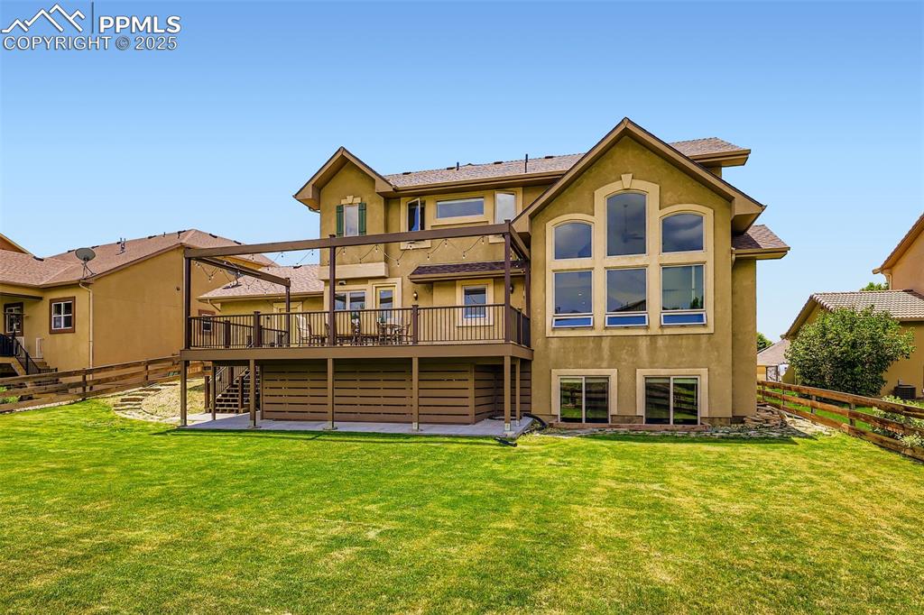 Rear view of house with stairs, a custom composite deck, a fenced backyard, and stucco siding