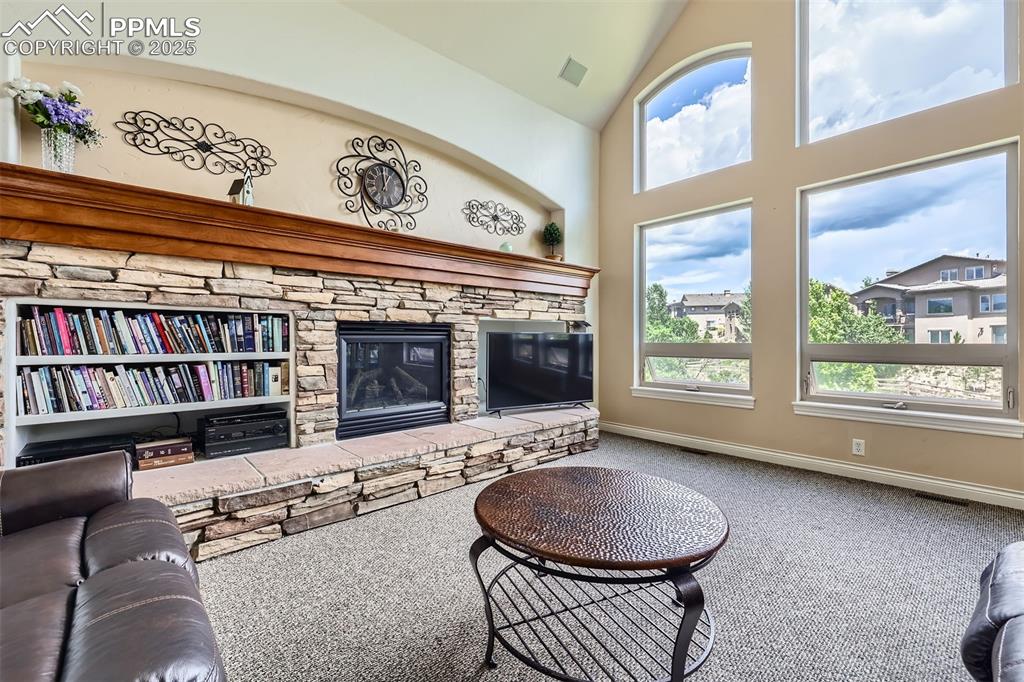 Carpeted living room featuring a fireplace and high vaulted ceiling