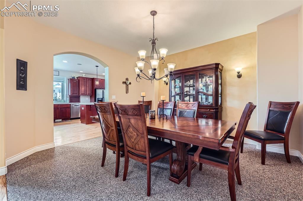 Dining area featuring arched walkways, a chandelier, and light carpet