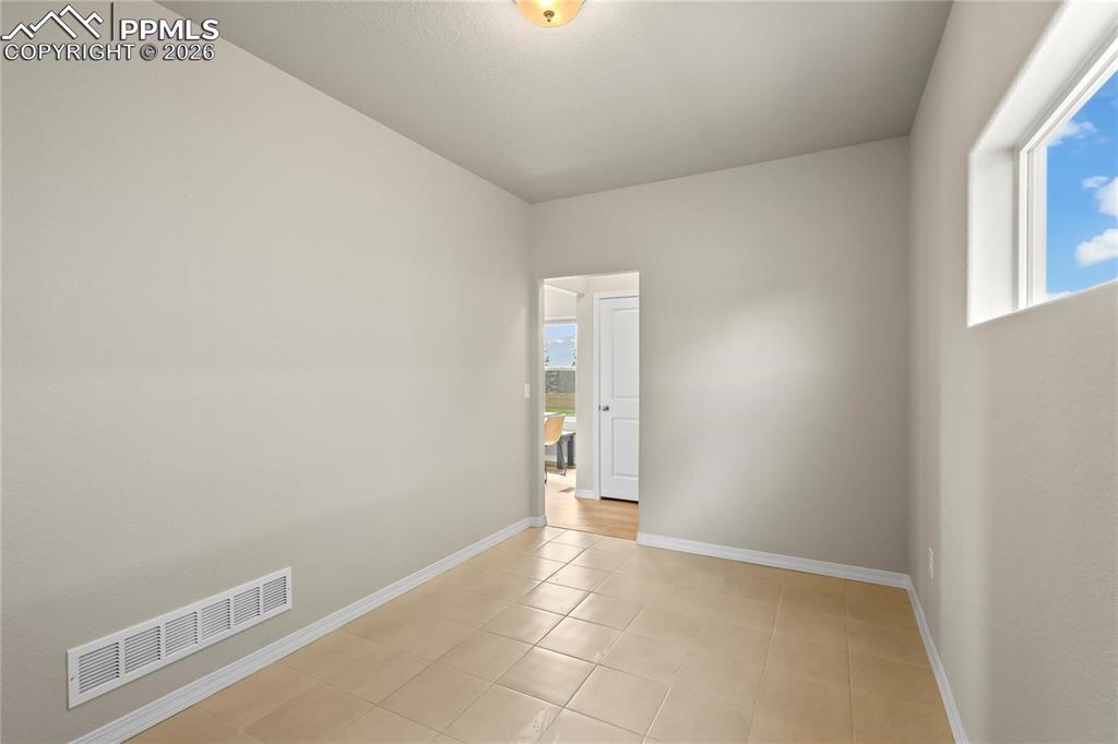 Empty room with baseboards and light tile patterned floors