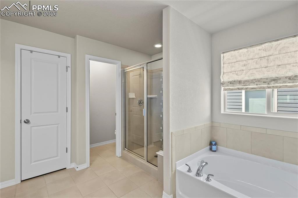 Full bath with a stall shower, a bath, and light tile patterned flooring