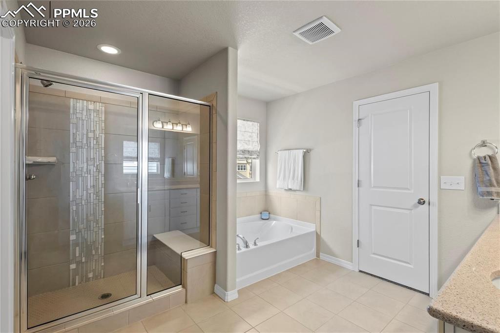 Full bath with a stall shower, a bath, vanity, light tile patterned floors, and recessed lighting