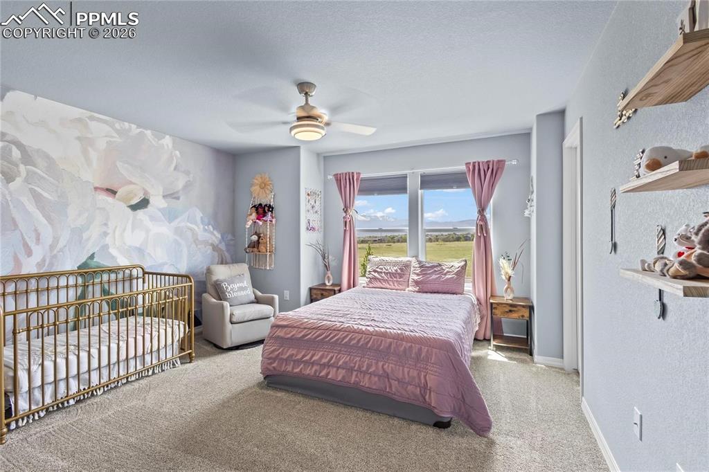 Carpeted bedroom with ceiling fan and a textured wall