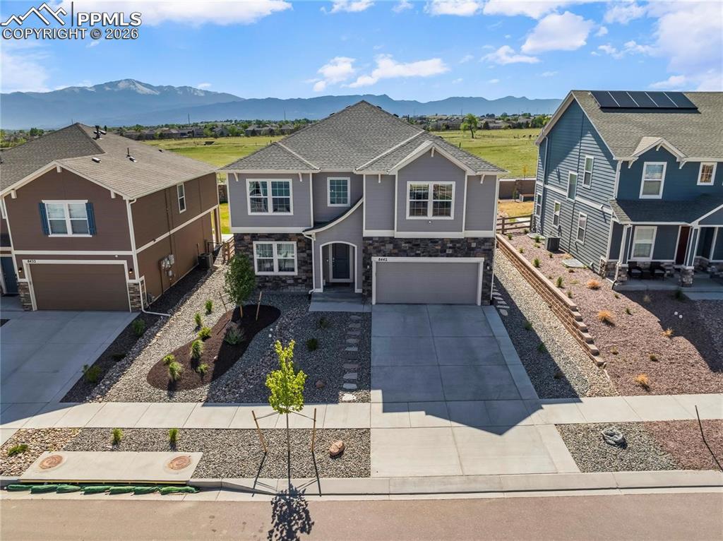 Craftsman-style home featuring an attached garage, driveway, stone siding, and a mountain view