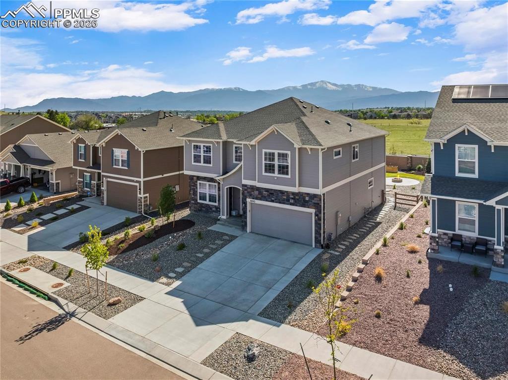 View of front of home featuring a garage, a mountain view, concrete driveway, and stone siding