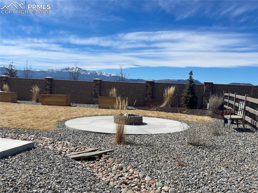 Fenced backyard featuring a patio, a mountain view, and a fire pit