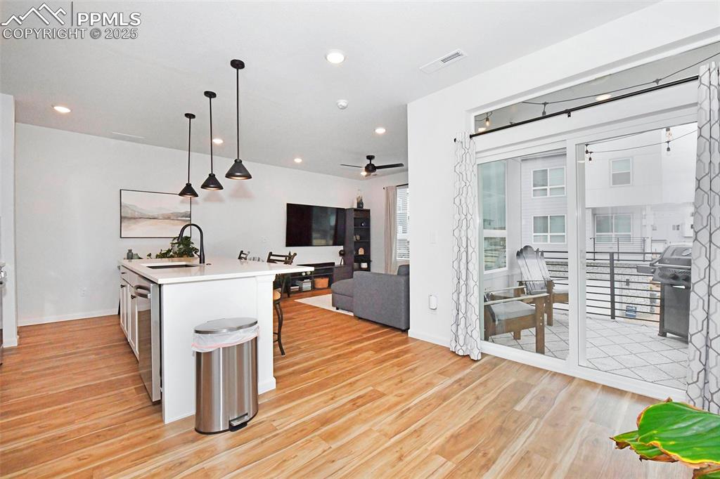 Kitchen featuring hanging light fixtures, an island with sink, open floor plan, light wood-style flooring, and recessed lighting